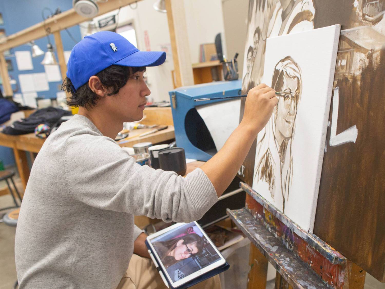 Student in blue hat drawing in a studio