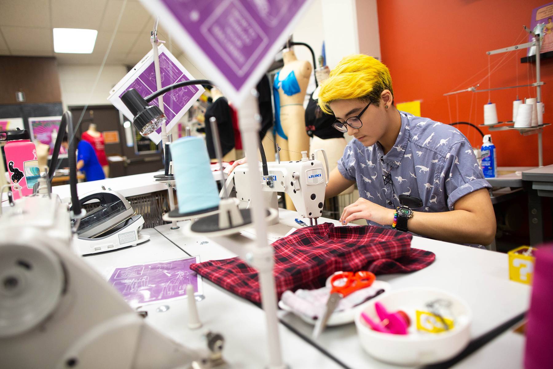 male student with bleached hair sewing an outfit