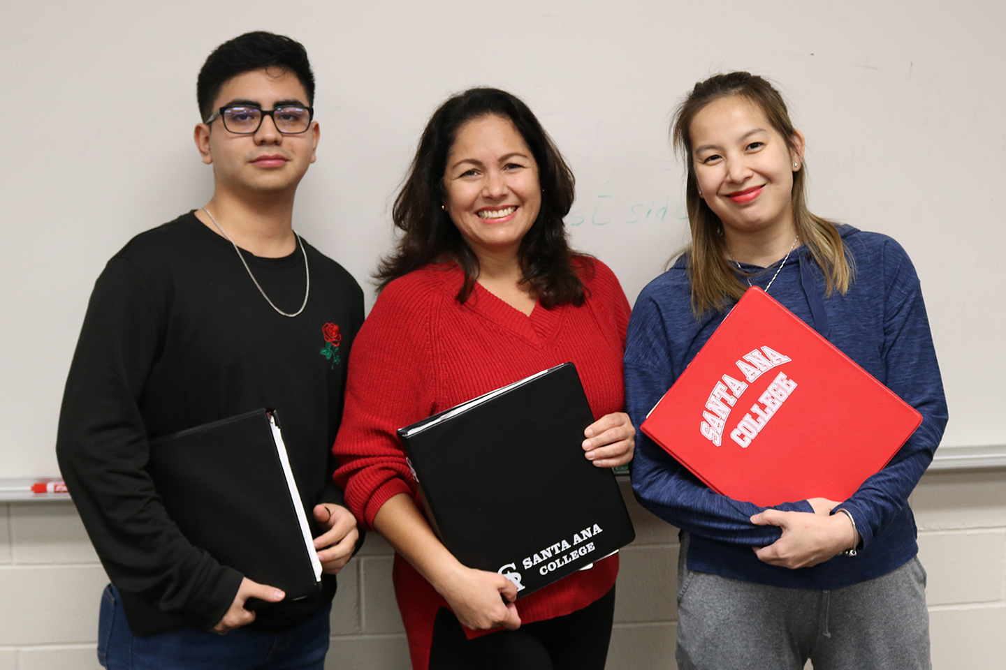 hispanic male, hispanic female, and asian female posing in front of whiteboard
