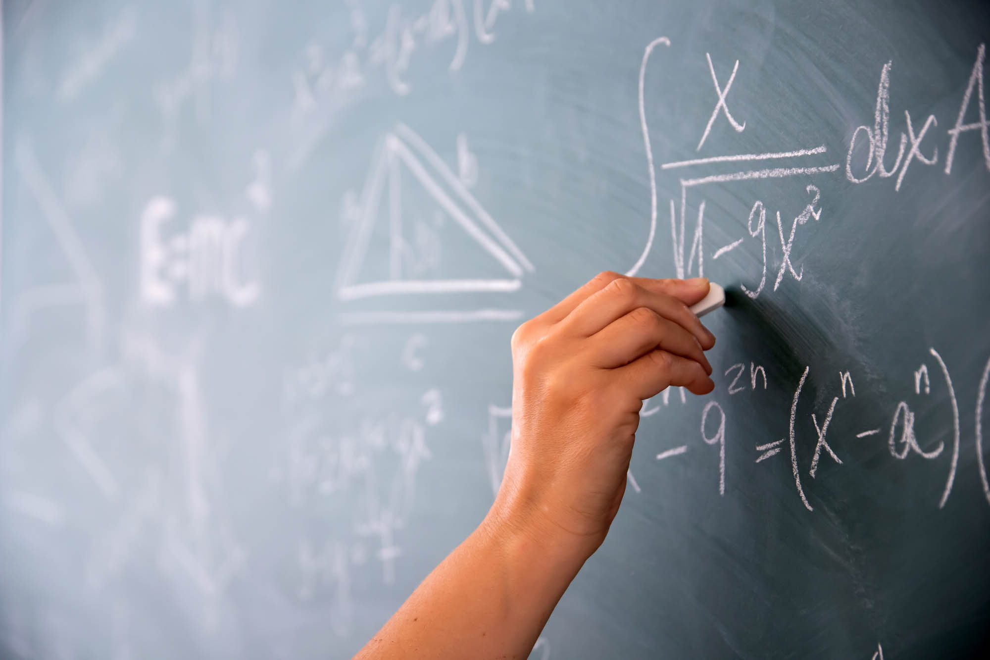 hand writing math formulas on chalkboard