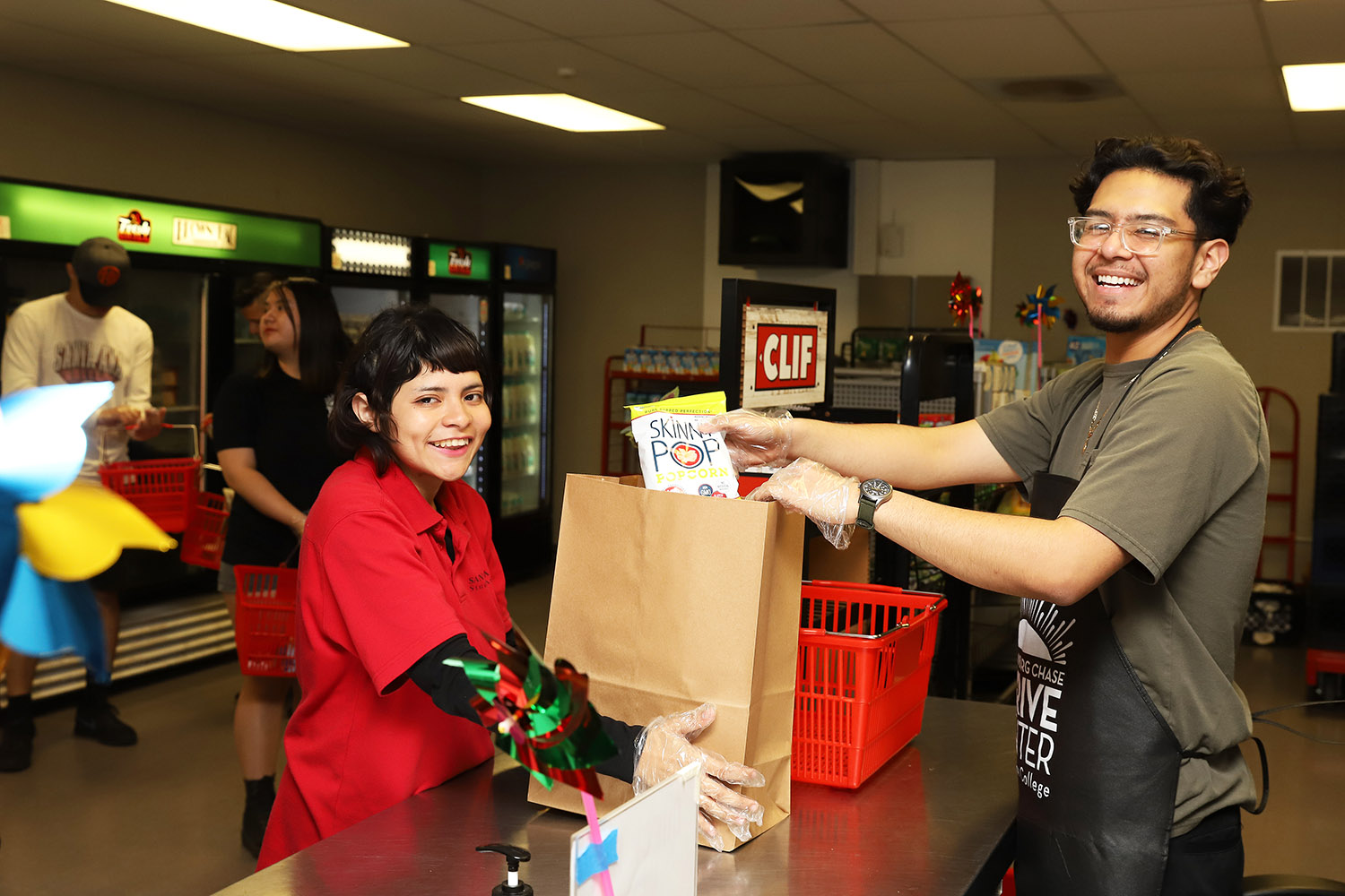 female student picking up groceries at counter from male worker