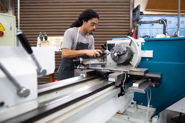 Asian Man operating heavy machine after learning manufacturing technology from Santa Ana College