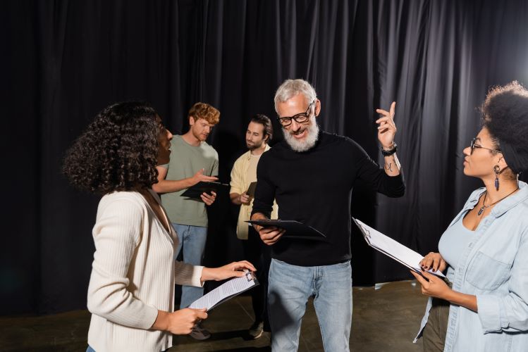 bearded art director guiding student actors while reading screenplay during acting skills lesson. at Santa Ana College