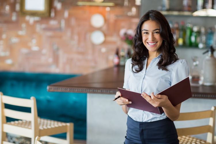 Smiling mixed race woman serving customers  using hospitality skills gained from free classes in Orange County