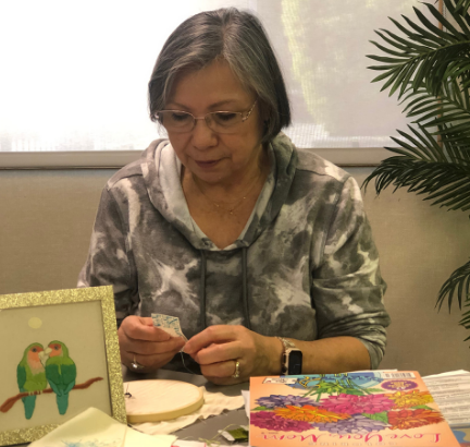 Woman displaying embroidery projects after studying in older adults class with Continuing Education.