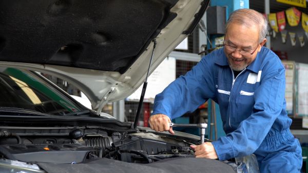 Older Asian man excited to fix car engine with skills from Santa Ana College Career Education Program