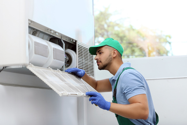 Man in green hat performing HVAC maintenance after getting certification from continuing education
