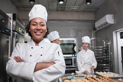 African American woman in chef's uniform excited to use the culinary skills learned from free classes at Santa Ana College