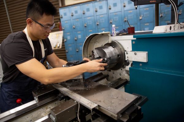 Asian Man operating heavy machine after learning manufacturing technology from Santa Ana College